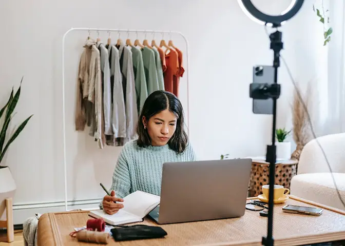 small business owner using a laptop to manage online and in-store clothing sales workspace scene