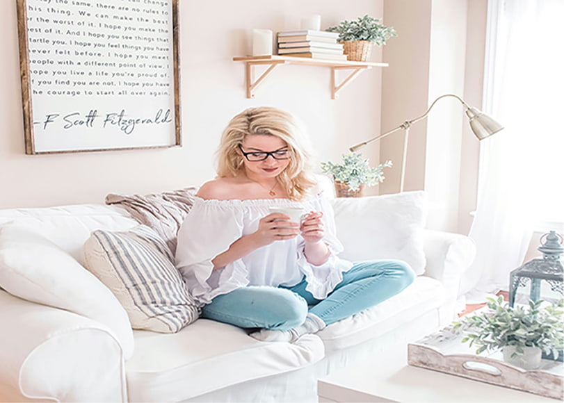 The woman sitting on the white sofa reading tips that Etsy sellers need to know