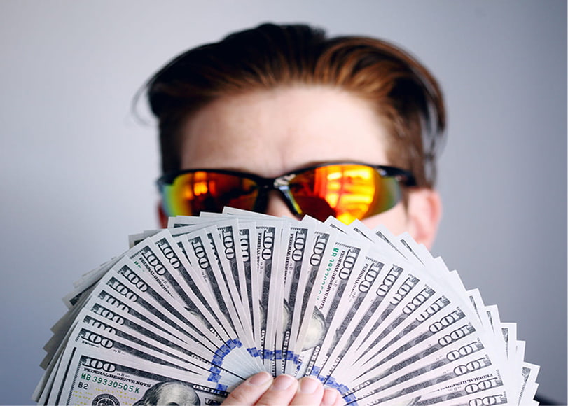 The man wearing sunglasses is showing off the money he has earned