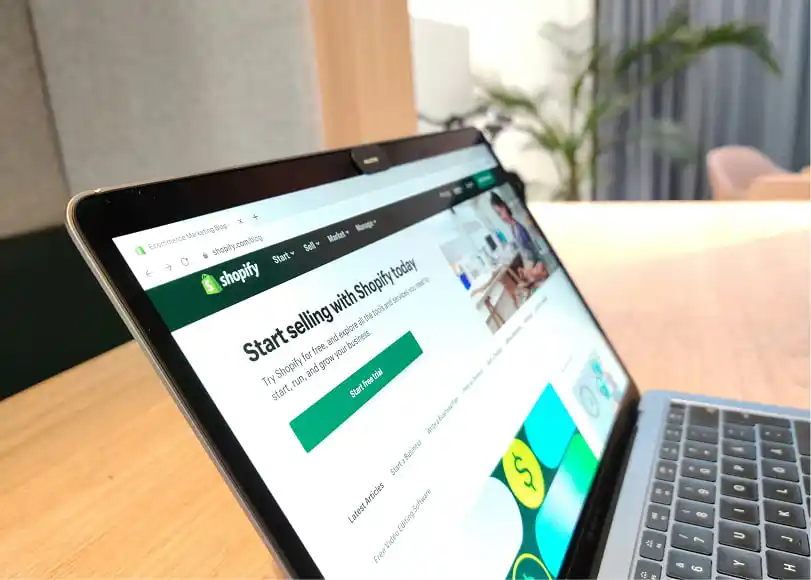 A guide on how to make money by selling T-shirts using Shopify displayed on the laptop.