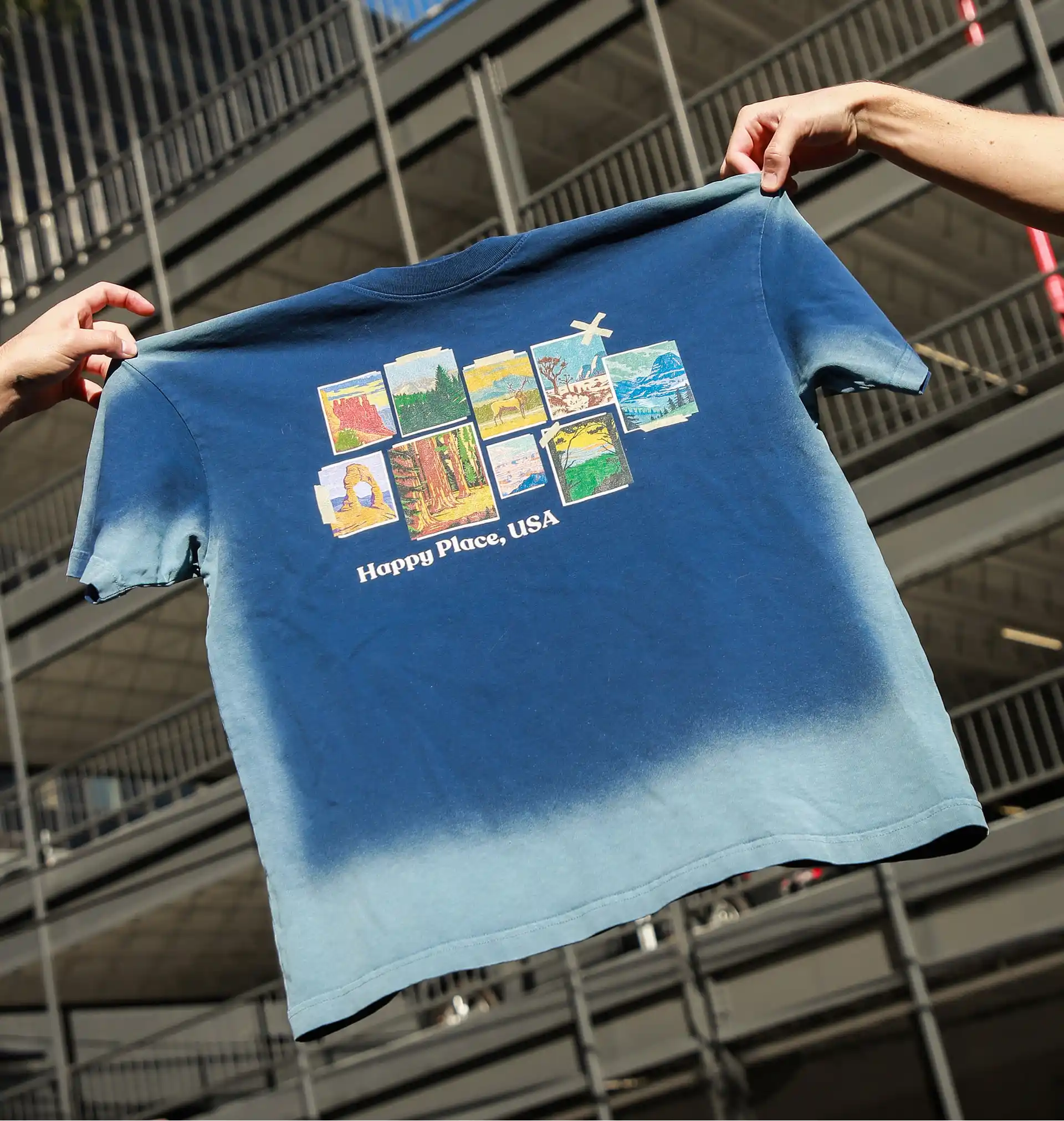 Two hands holding the water-washed printed T-shirts made by tapstitch.