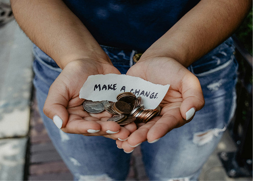 Woman displaying coins and a note reading “Make a Change